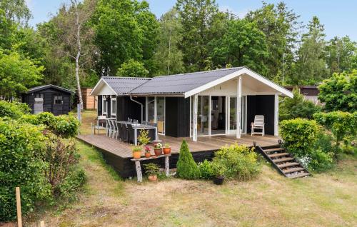 a black and white cabin with a deck at 2 Bedroom Pet Friendly Home In Knebel in Knebel