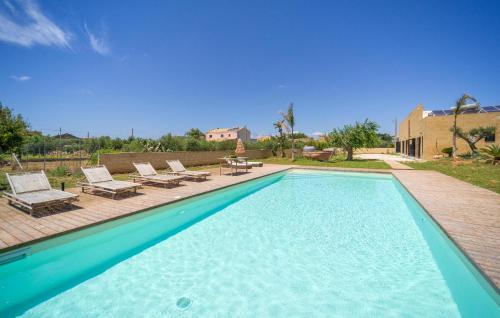 a swimming pool with chaises and chairs next to a house at Amazing Home In Marsala With Wifi in Marsala