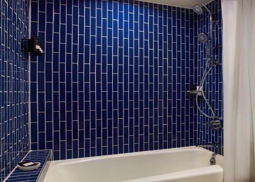 a blue tiled bathroom with a white bath tub at The Highland Dallas, Curio Collection by Hilton in Dallas