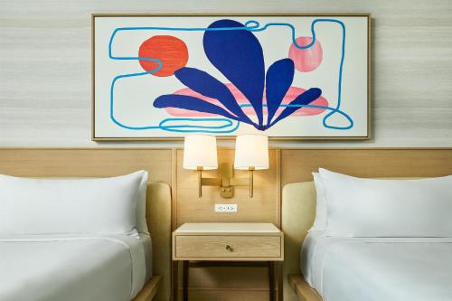 a hotel room with two beds and a painting on the wall at The Highland Dallas, Curio Collection by Hilton in Dallas