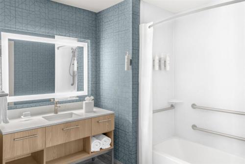 a bathroom with a sink and a tub and a mirror at Homewood Suites by Hilton Fayetteville in Fayetteville