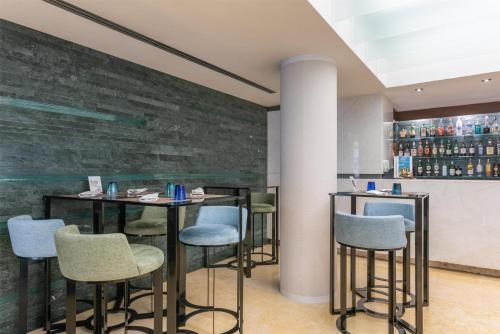 a bar with stools in a room with a stone wall at Hilton Garden Inn Rome Claridge in Rome
