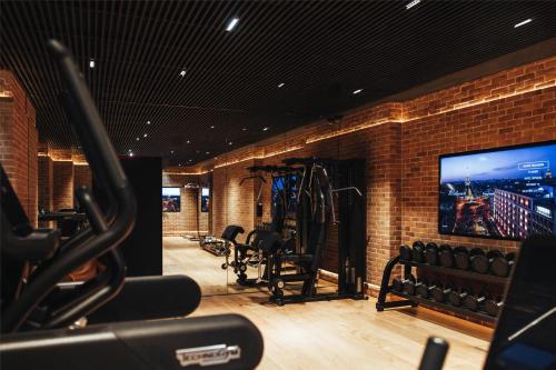 a gym with bikes and a tv in a brick wall at Hotel SAX Paris, LXR Hotels & Resorts in Paris