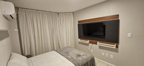 a hotel room with a bed and a flat screen tv at Apto 2 Quartos com Suíte, Garagem, 300m da Praia in Fortaleza