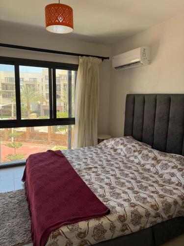 een slaapkamer met een bed en een groot raam bij 1 Bedroom at Marassi Marina in El Alamein