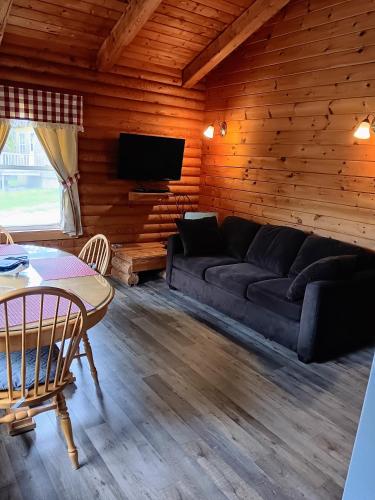 a living room with a couch and a table at Cajun Cedar Log Cottages in Margaree Forks