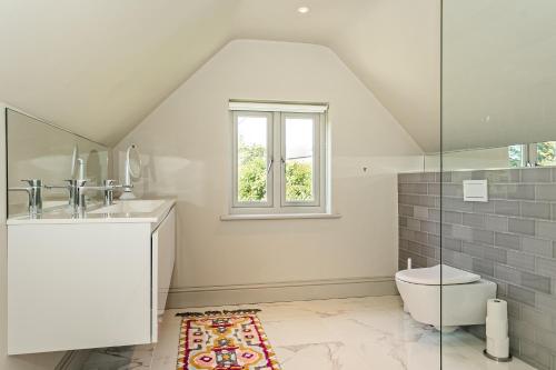 a bathroom with a sink and a toilet and a window at Field House - Stunning 3 Bedroom Home in Kingham! in Kingham