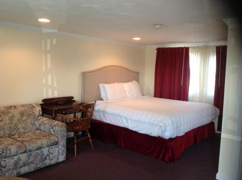 a bedroom with a bed and a chair and a couch at Tides Motel - Hampton Beach in Hampton