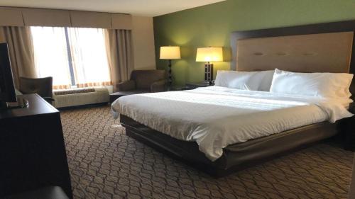 a hotel room with a large bed and a chair at Holiday Inn Express and Suites Winchester by IHG in Winchester