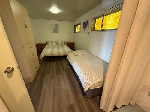 a small bedroom with two beds and a window at Comfortable studio in Bowen 4805 in Bowen