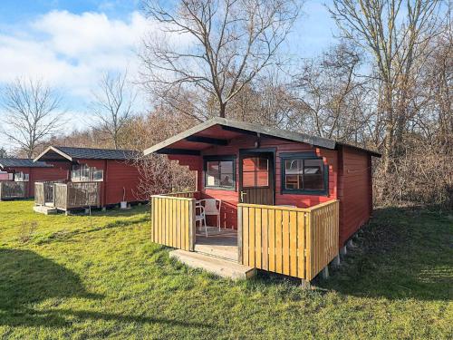 a small red house with a deck in the grass at Holiday home for family Denmark in Gørlev