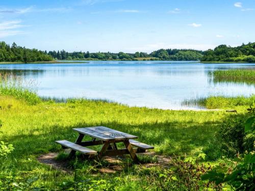 a picnic table sitting in the grass near a lake at 4 person holiday home in Hampen in Hampen