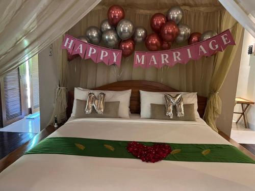 a bed with a happy marriage sign and balloons at DISINI Luxury Spa Villas-CHSE Certified in Seminyak
