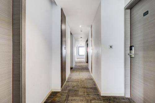 a hallway with white walls and a wooden floor at Sleek Townhouse Galexia Hotel and Resorts in Bengaluru