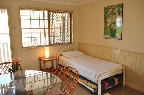 a small room with a bed and a glass table at Isla House PA in Brisbane