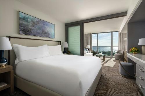 a bedroom with a large white bed and a living room at The Ritz-Carlton Residences, Waikiki Beach Hotel in Honolulu
