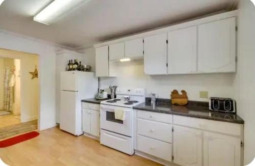 a kitchen with white cabinets and white appliances at Coastal Charm in Bay Saint Louis