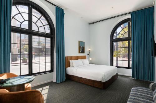 a bedroom with a bed and two large windows at The Guild Hotel San Diego Downtown, a Marriott Tribute Portfolio Hotel in San Diego