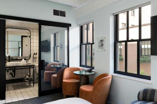 a bathroom with two chairs and a sink and a mirror at The Guild Hotel San Diego Downtown, a Marriott Tribute Portfolio Hotel in San Diego