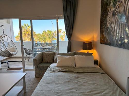 een slaapkamer met een bed en een stoel en een balkon bij Callao Sunset Home in Callao Salvaje