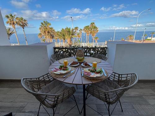 een tafel met borden eten op een balkon met uitzicht op de oceaan bij Callao Sunset Home in Callao Salvaje