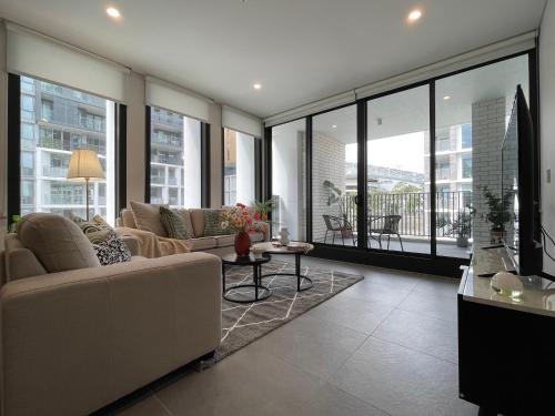 a living room with a couch and a table at Nearby stadium & New 3b2b Apt & Free parking in Sydney