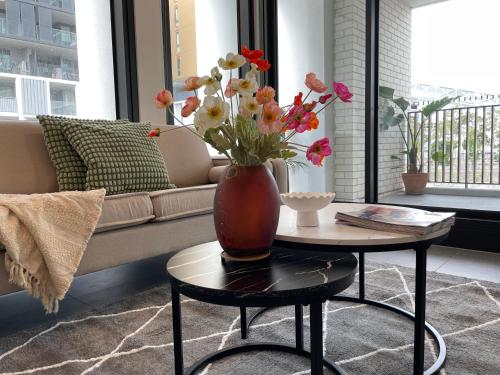 a vase with flowers on a table in a living room at Nearby stadium & New 3b2b Apt & Free parking in Sydney
