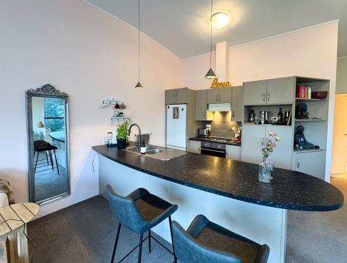 a kitchen with a counter and blue chairs in it at 3BR Lakeview Home with Balcony, Parking, Near Marina in Queenstown