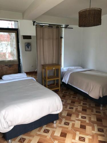 a room with two beds and a table in it at Vertigo Climbing Hostel in Urubamba