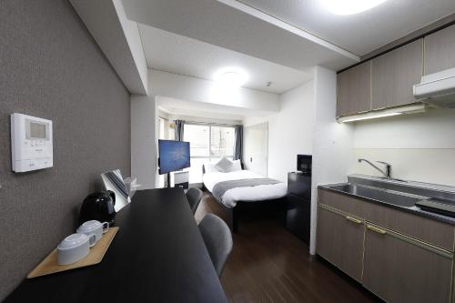 a small hotel room with a bed and a kitchen at クレストコート北大前 in Sapporo
