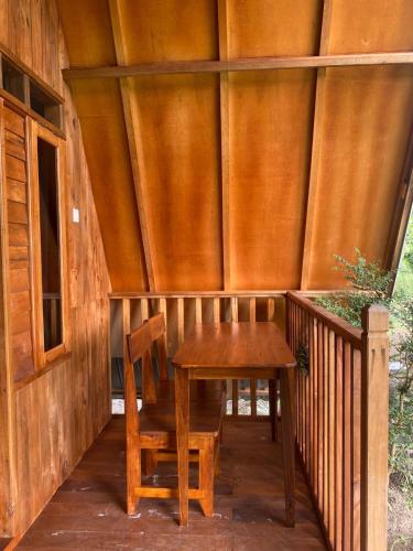 a wooden porch with a wooden table and a chair at Forest Side bungalow in Tetebatu