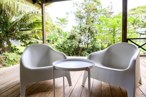 two white chairs and a table on a deck at The Pavilion - Rarotonga in Arorangi