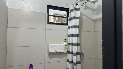 a bathroom with a shower with a black and white shower curtain at Villa Nola Dos in Port-of-Spain