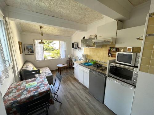 - une cuisine avec des appareils électroménagers blancs et une table dans l'établissement Appartement T2 proche plage avec terrasse - FR-1-837-16, à Argelès-sur-Mer