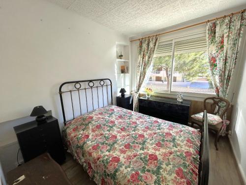 - une chambre avec un lit doté d'un couvre-lit floral et d'une fenêtre dans l'établissement Appartement T2 proche plage avec terrasse - FR-1-837-16, à Argelès-sur-Mer