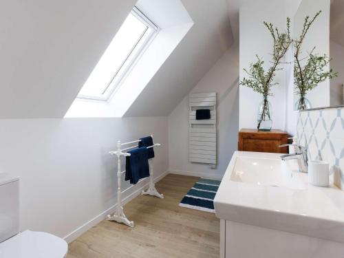 La salle de bains blanche est pourvue d'un lavabo et d'une lucarne. dans l'établissement Maison 4 étoiles à Trégastel, proche plage pour 8 pers. avec parking - FR-1-542-74, à Trégastel