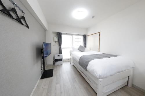 a bedroom with a white bed and a tv at クレストコート北大前 in Sapporo