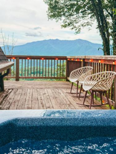 a deck with two chairs and a swimming pool at Big Mountain View! Downtown Gatlinburg Chalet Village! Hot Tub! Fan Favorite! AFrame Dreams! Magazine-Featured! Stunning Interiors! Little Green Cabin in Gatlinburg