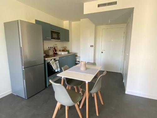 une cuisine avec une table, des chaises et un réfrigérateur dans l'établissement Appartement Moderne avec Parking à Argelès-sur-Mer - FR-1-732-98, à Argelès-sur-Mer