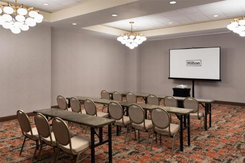 a conference room with tables and chairs and a screen at Embassy Suites North Charleston Airport Hotel Convention in Charleston