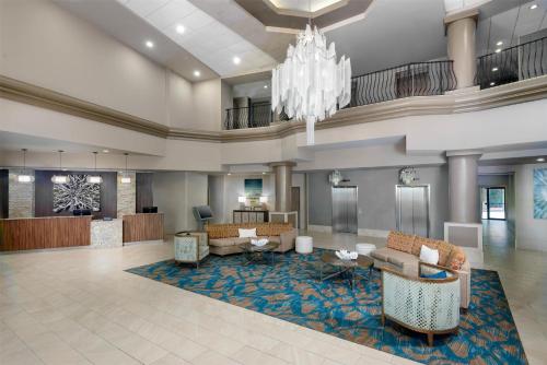 a lobby of a hotel with couches and a chandelier at DoubleTree by Hilton Hotel West Palm Beach Airport in West Palm Beach