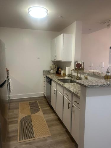 a kitchen with white cabinets and a wooden floor at The Monroe Elegant 2br2ba Downtown Stamford in Stamford