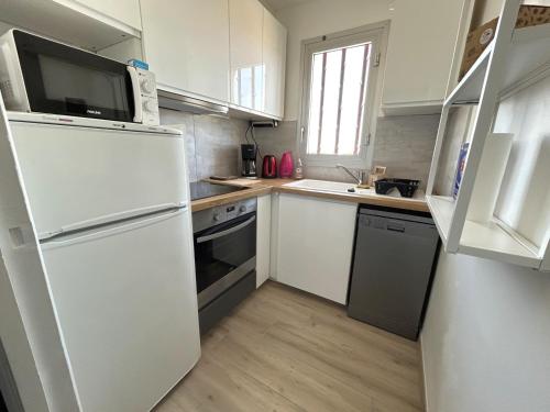 une cuisine avec des armoires blanches et un réfrigérateur blanc dans l'établissement Appartement spacieux 4 pers avec terrasse et parking - FR-1-837-1, à Argelès-sur-Mer