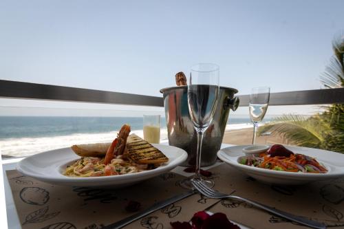a table with two plates of food and a glass of wine at Hotel Playa Paraíso in Monterrico
