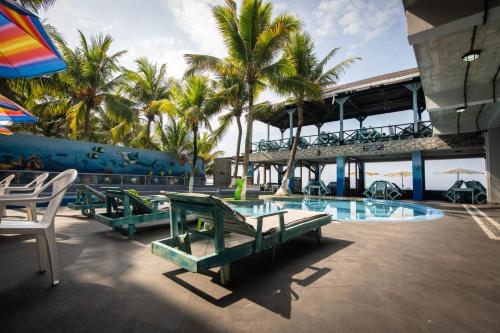 a resort with a pool with chairs and palm trees at Hotel Playa Paraíso in Monterrico
