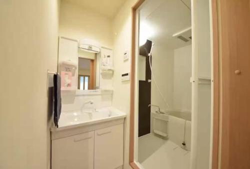 a white bathroom with a sink and a mirror at 盛-大正 in Osaka