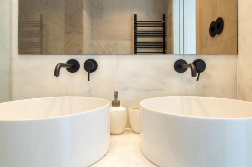 two white sinks in a bathroom with a mirror at EDiTiON 309 - Luxury Seafront 2BR Apartments in Porto