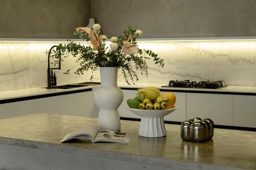 a vase with flowers and a bowl of fruit on a table at Predmet Babakan Canggu Bali in Dalung