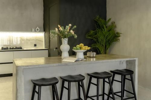 a kitchen with a counter with four bar stools at Predmet Babakan Canggu Bali in Dalung