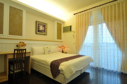 a bedroom with a bed and a desk and a window at 朝日民宿 可包棟 in Taitung City